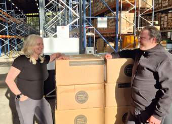 Scene: A man and a woman, with a pile of cardboard boxes between them, are laughing at each other.
